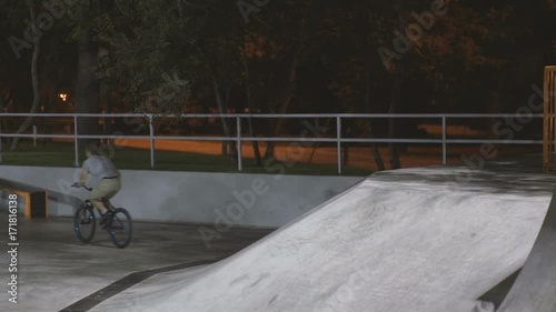 MTB bicycle rider does various tricks while riding in skatepark . Extreme Sports, rider does tabletop trick at night  photo