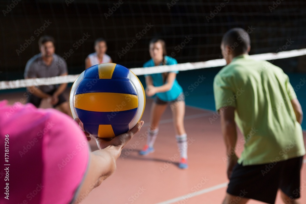 Cropped hand of player with teammates holding volleyball