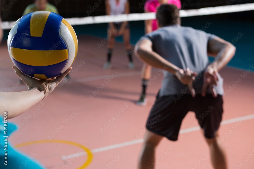 Fototapeta premium Cropped image of player with teammates holding volleyball