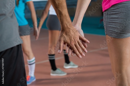 Mid section of volleyball players holding hands