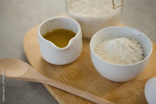 Flour and oil in containers on cutting board