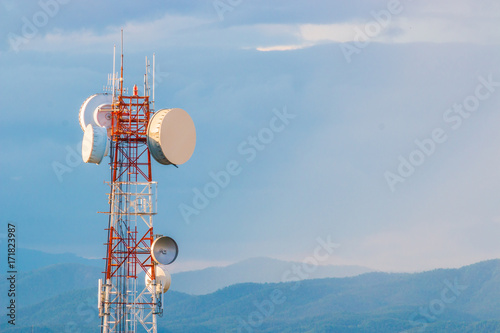 telecommunication tower with mountain range background with warm sunset light casting on clouds