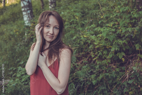 Young woman portrait in a summer forest in the mountains. Pretty girl in red dress in summertime