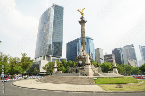 Marble column with golden monument in form an angel girl on top at background of skyscrapers in Mexico City center
