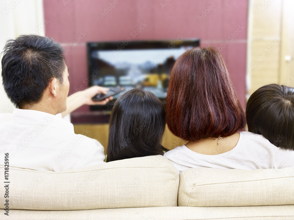 asian family with two children watching TV together asian family with two children watching TV together