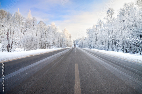 winter landscape with asphalt road,forest and blue sky.