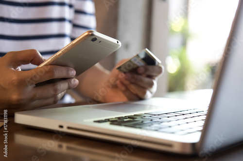 Hands holding credit card, mobile phone and using laptop. Online shopping, Travel booking concept. Selective focus.