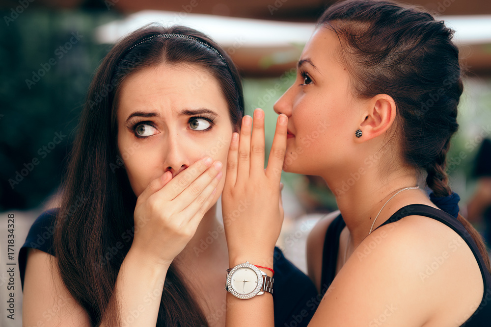 Indiscrete Gossiping Girl Telling Secrets to her Surprised Friend 