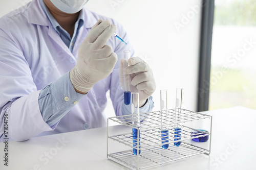 Scientist or medical in lab coat holding test tube with reagent with drop of color liquid over glass  Biochemistry laboratory research