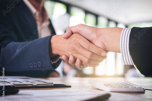 Two smiling businessman shaking hands together after good deal connection to join investment business