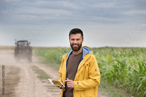 Farmer holding tablet with tractor behind