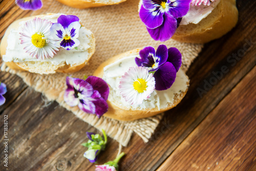 Sandwich with herb and edible flowers butter on marble cutting board. Healthy food.