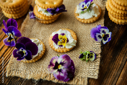 Sandwich with herb and edible flowers butter on wooden background, healthy food.