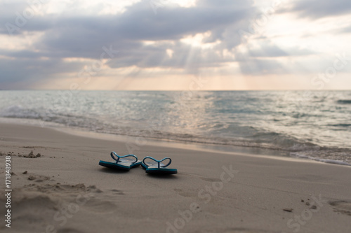 beach slippers on the sand at sunset and sea