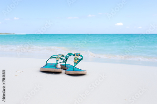 beach slippers on white sand on the background of azure sea