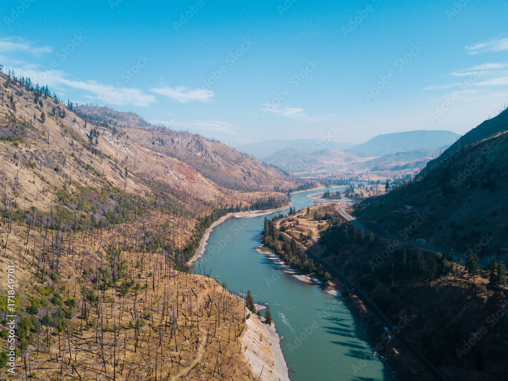 Aerial shot above blue river in grassland canyon