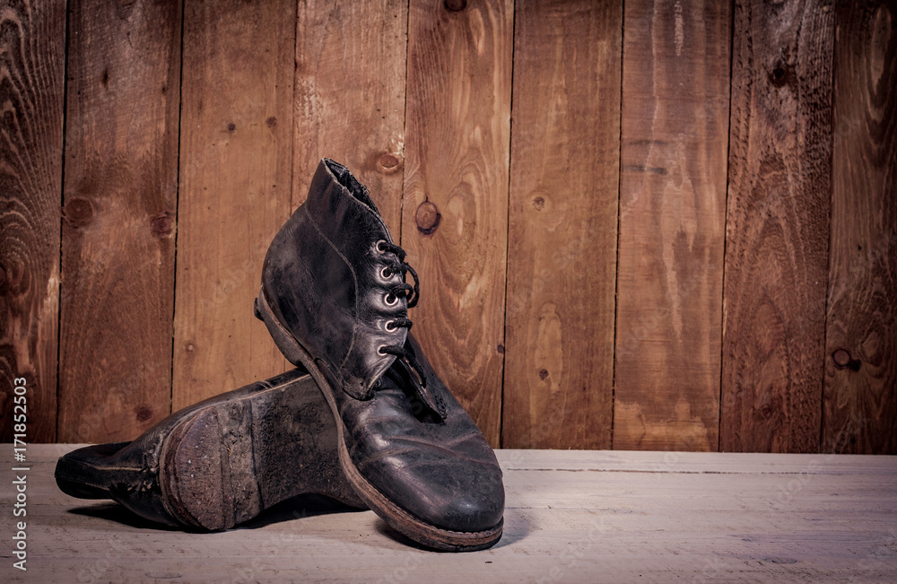 Old leather boots on dirt wooden background  