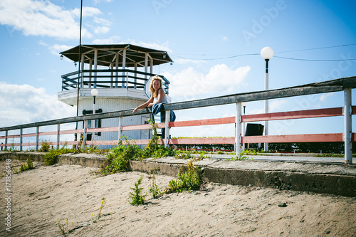 young beautiful woman in jeans clothes outdoors. portrait of a girl with freckles on her face, stylish girl on sea beach, on a sunny summer autumn day.