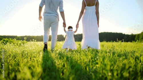 Family walks in the Park and baby daughter taking her first steps. All dressed in white and under the setting sun. photo