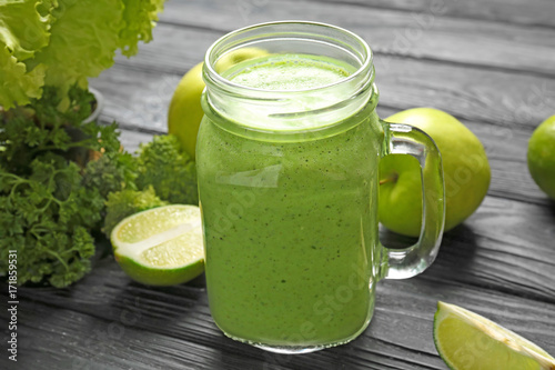 Mason jar with fresh green smoothie on wooden table