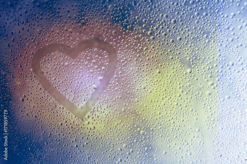 Heart drawn on misted glass covered with droplets. Autumn rain