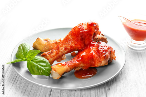 Tasty chicken legs with tomato sauce on wooden table