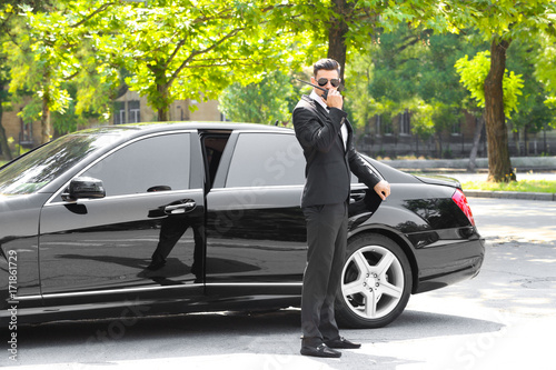 Handsome bodyguard near car outdoors photo