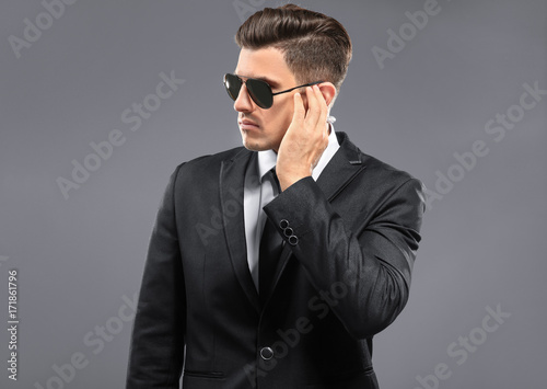 Handsome security guard on grey background photo