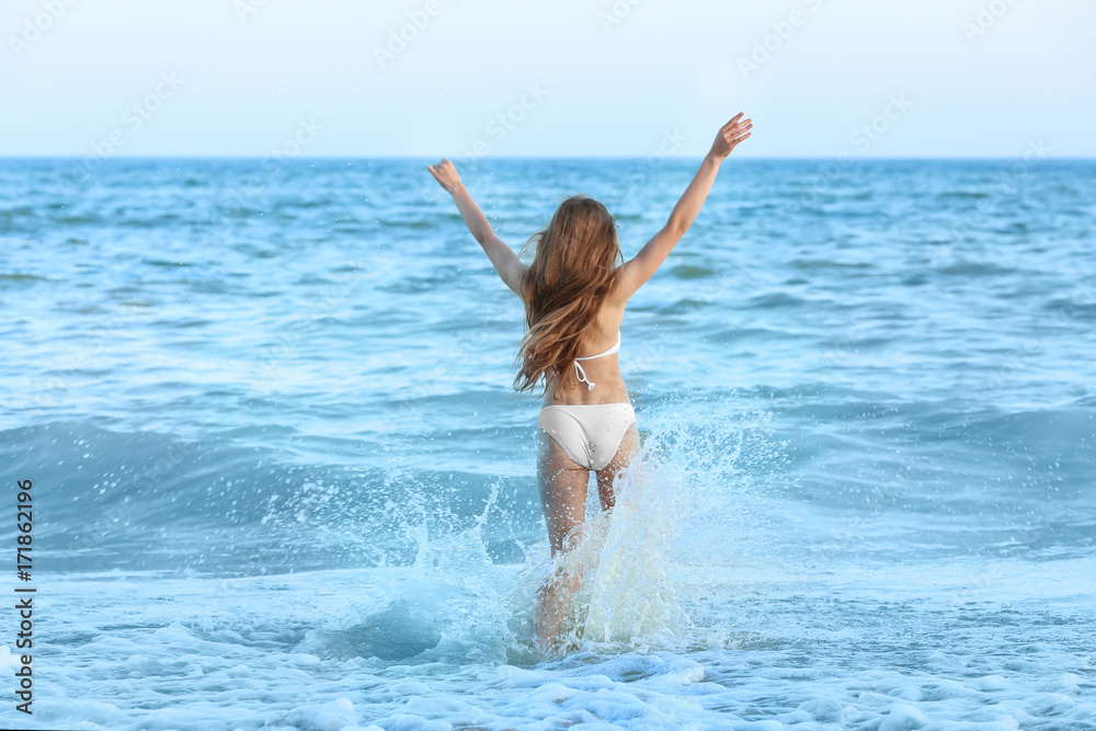 Beautiful young woman bathing in sea