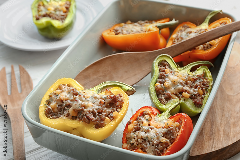Quinoa stuffed peppers and wooden spoon in baking dish