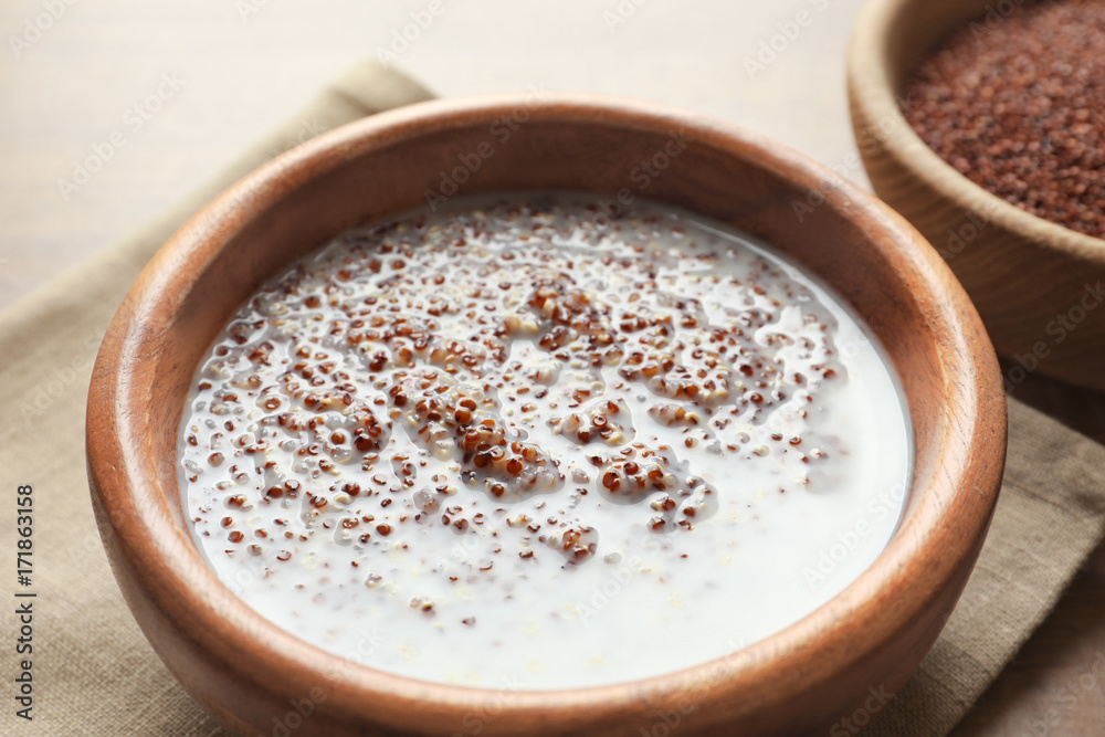 Bowl with boiled quinoa grains and milk on wooden table Bowl with boiled quinoa grains and milk on wooden table