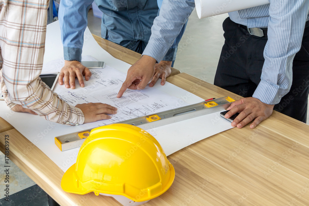 A group of engineers are looking at a blueprint for construction. A group of engineers are looking at a blueprint for construction.