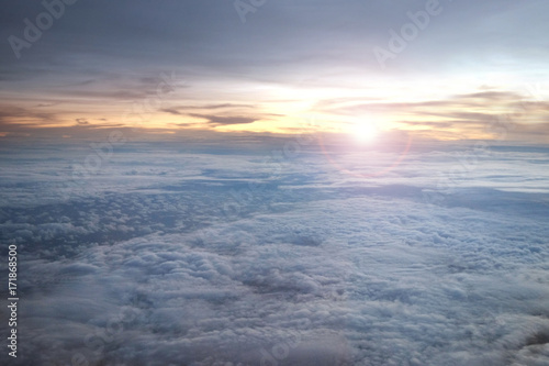 Beautiful cloudscape above the sky with the sunrise at the horizon from the window of an airplane