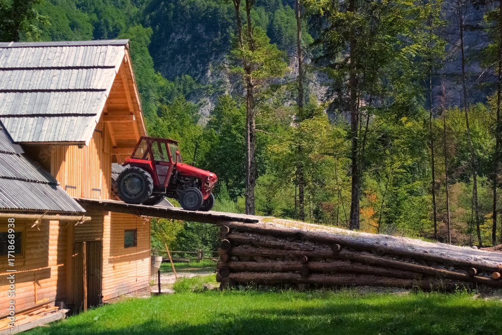 Rustic old red tractor on ramp of wooden barn
