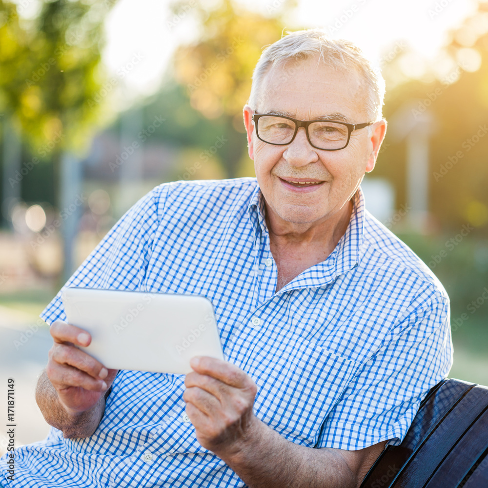 Outdoor portrait of happy senior man who is using digital tablet. Outdoor portrait of happy senior man who is using digital tablet.