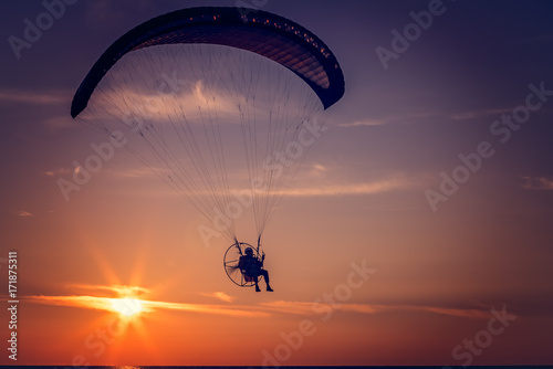 Paraglider flying at sunset