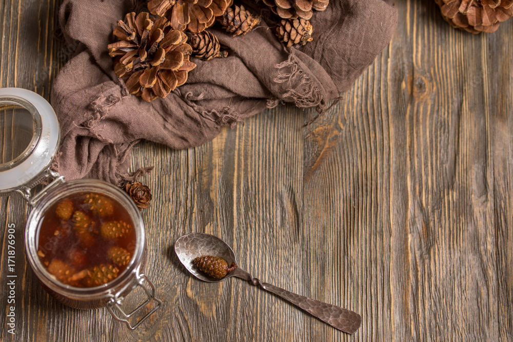 A jar of homemade jam made of pine cones on a dark wooden background. Frame for the text. A jar of homemade jam made of pine cones on a dark wooden background. Frame for the text.