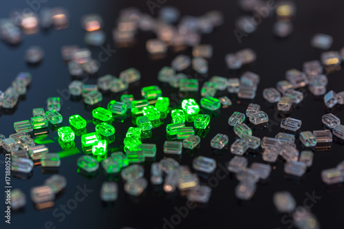 Obraz na plátně Transparent glass beads on black background illuminated by green laser
