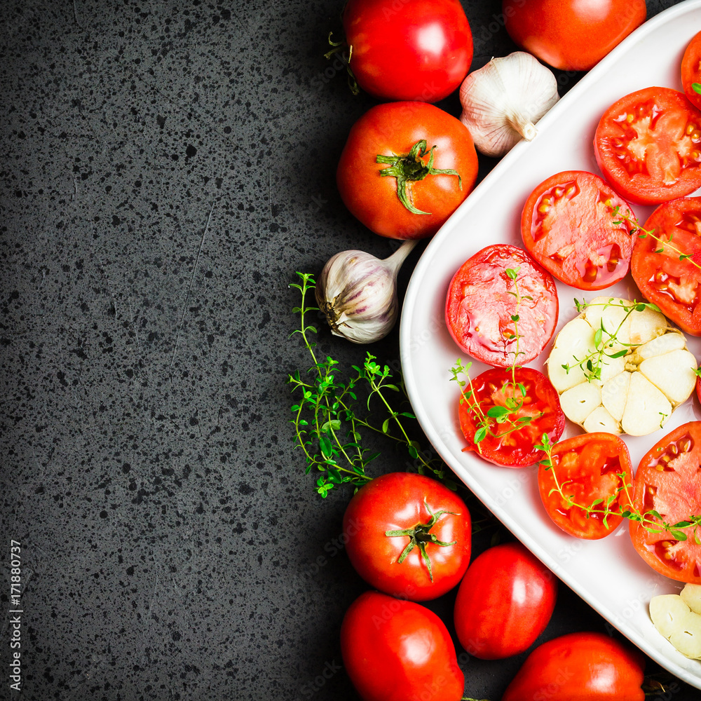 Tomatoes, garlic and thyme on dark background. Top view, space for text. Tomatoes, garlic and thyme on dark background. Top view, space for text.