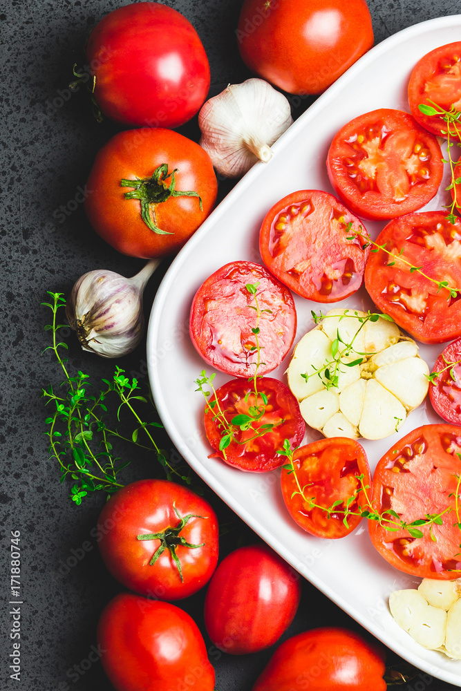 Tomato slices in a baking dish with garlic and thyme. Top view, space for text. Tomato slices in a baking dish with garlic and thyme. Top view, space for text.
