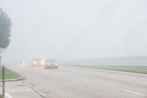 Valokuvatapetti Morning foggy city frontage road with traffic sign and car silhouette in Humble, Texas, USA