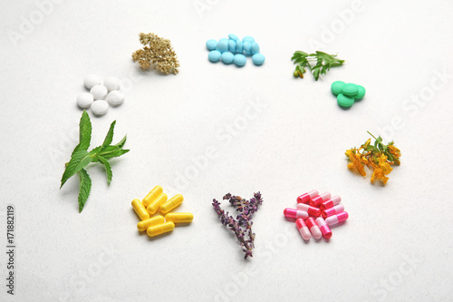 Colorful pills and herbs in shape of circle on white background
