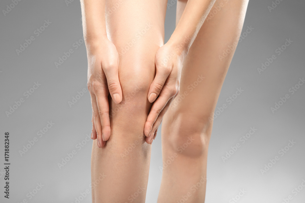 Young woman suffering from pain on gray background Young woman suffering from pain on gray background