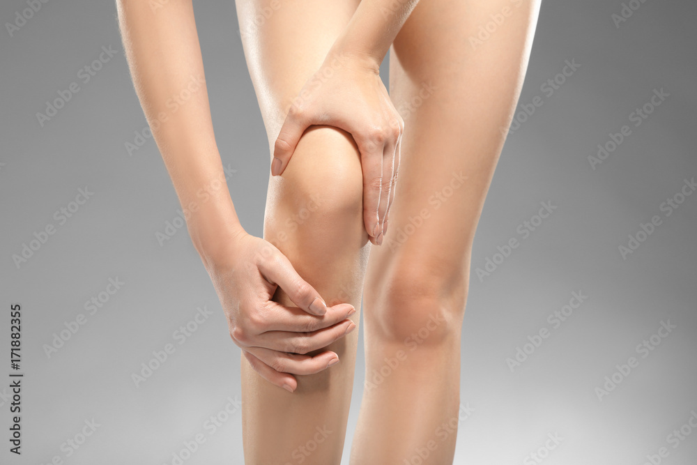 Young woman suffering from pain on gray background