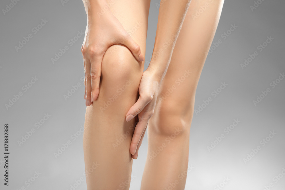Young woman suffering from pain on gray background Young woman suffering from pain on gray background