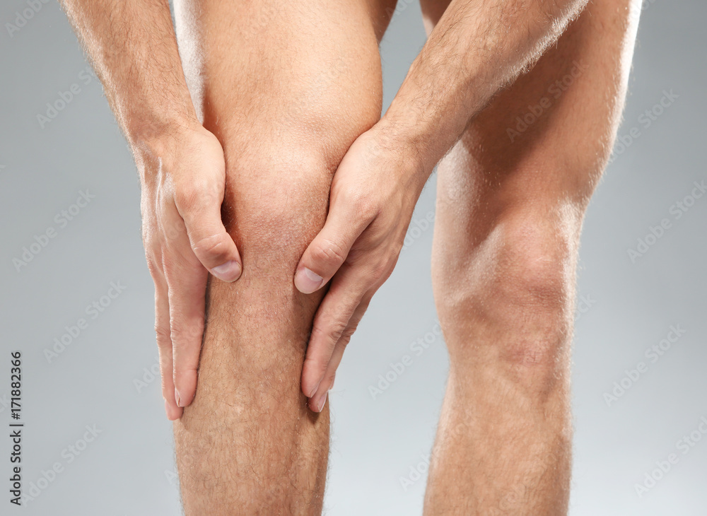 Young man suffering from pain on light background Young man suffering from pain on light background