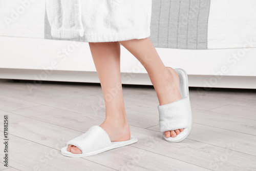 Woman standing in white spa slippers on grey parquet