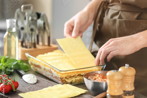 Foto Woman preparing meat lasagna in kitchen