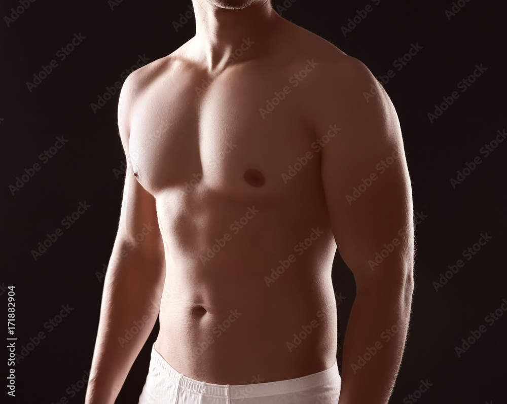 Fototapeta premium Sporty young man on dark background