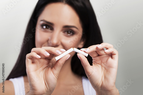 Quit Smoking. Closeup Of A Beautiful Happy Woman Breaking A Cigarette. Portrait Of A Smiling Woman Holding A Broken Cigarette In Hands. Healthy Lifestyle Concept.